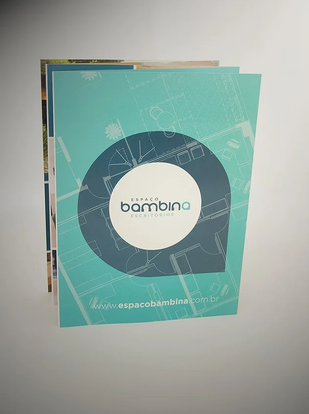 Capa do folder do Espaço Bambina Escritórios em verde-água, com a marca dentro de um balão sobre a planta baixa.