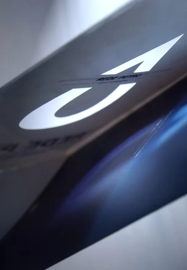 Detalhe da capa da Rede Petro: a gota da marca em branco sobre azul e cinza, em ângulo.